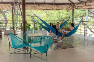 a group of people sitting in hammocks in a room at The Cantamar Beach Hostel in Santa Marta