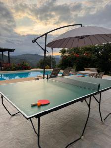 a ping pong table with an umbrella next to a pool at Cabañas Alondra - Hotel Boutique in Vergara