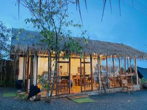 a house with a straw roof with chairs and a table at เลอดอย Le Doi in Ban Huai Khai