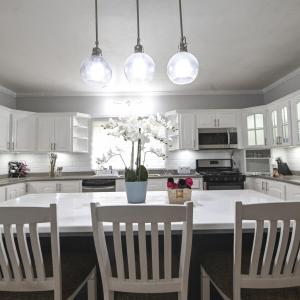 a kitchen with white cabinets and a table with chairs at Dr Doc's Family Lodge with Pool in Spur Tree