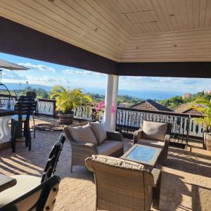 an outdoor patio with chairs and tables and a view of the ocean at Dr Doc's Family Lodge with Pool in Spur Tree