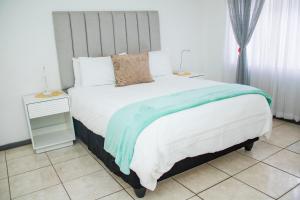 a bedroom with a large bed and two night stands at 1 bed apartment in Harare CBD in Harare