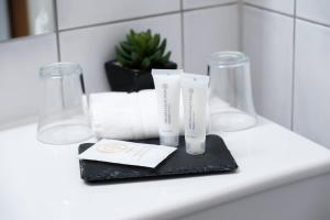 a bathroom counter with two complimentary toothbrushes and towels at Hôtel du Port in Lausanne