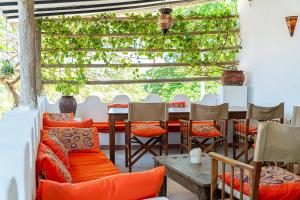 a dining room with a table and chairs with orange pillows at Ella's Swahili Villa - Restored 1840s Heritage Home in Bagamoyo