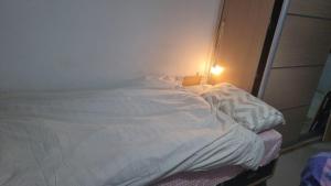 an unmade bed in a room with a light at Big Room Ashdod in Ashdod