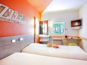 a hotel room with two beds and a television at Ibis Budget Fréjus Capitou in Fréjus