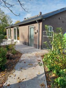 a brick house with a green door and a driveway at Gastenverblijf De Lopende Eend in Boxtel +10 photos