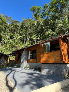 a house with a wooden facade with trees in the background at Chale Allegra - Hidro Aquecida - Vista para o Lago in Venda Nova do Imigrante