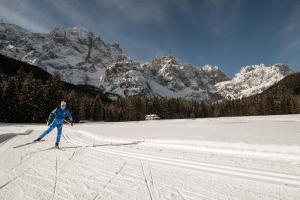 a woman on skis in the snow in front of mountains at Locanda Da Pierina in Santo Stefano di Cadore