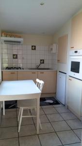 a kitchen with a white table and a white refrigerator at le Questel in Plouézec