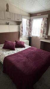 a bedroom with a purple bed with two purple pillows at WillowWay168, Tranquility Family Home in Camber +33 photos