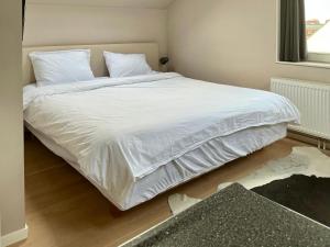 a bedroom with a bed with white sheets and a window at Oomes Huus - Sleep by Hästens, Wake with Coffee in Den Hoorn