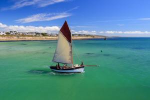 a small boat with a sail in the water at Gîte les Hirondelles in Plouhinec +6 photos