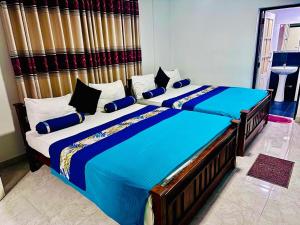 a bedroom with two beds with blue and white pillows at Silver Meir Villa in Nuwara Eliya +35 photos