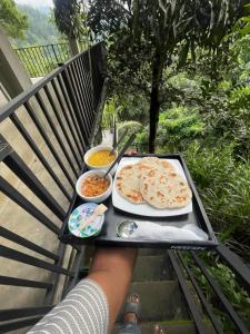 Eine Person, die ein Tablett mit Pizza auf einem Tisch hält. in der Unterkunft Crystal Resort in Badulla