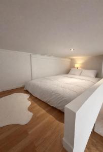 a bedroom with a large white bed and wooden floors at LB studio in Dunkerque