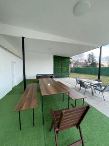 a group of tables and benches in a room with grass at Apartman na dan Pecinci in Pećinci +2 photos
