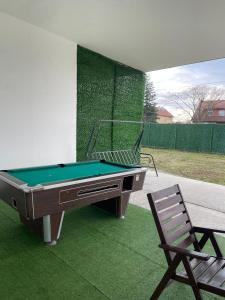 a pool table and a chair on a lawn at Apartman na dan Pecinci in Pećinci