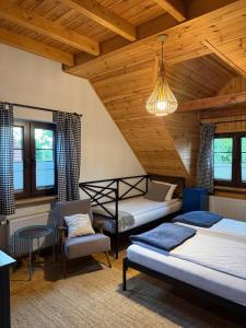 two beds and a chair in a room with wooden ceilings at Wypoczynek pod Lipami in Ruciane-Nida