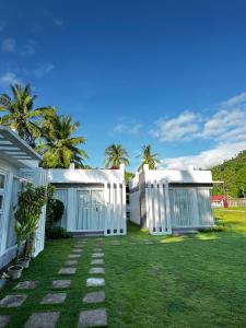 a yard with two white buildings and palm trees at Marinelli Beach Resort in San Agustin