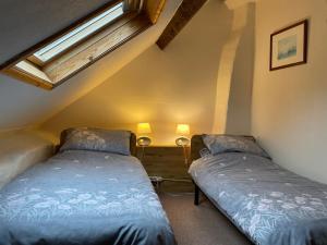 two beds in a small room with a window at Lavender Cottage in Chézelles