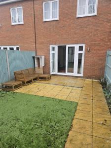 a patio with two benches in front of a brick building at The Brown Rest House in Gravesend