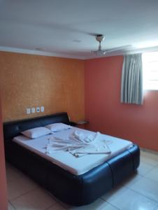 a bed in a room with a red wall at Motel pousada Zafira in Salvador