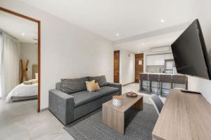 a living room with a gray couch and a tv at Swim-up 1-bedroom apartment in Playa del Carmen