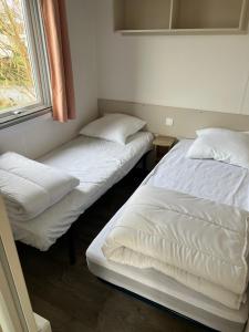 two beds sitting in a room with a window at Mobil Home Litteau Calvados in Litteau