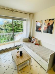 a living room with a couch and a table at Les Pins Marins, Proche plages in Saint-Jean-de-Monts