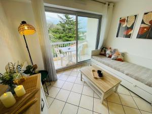 a living room with a couch and a table at Les Pins Marins, Proche plages in Saint-Jean-de-Monts