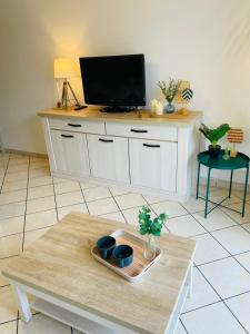 a living room with a table with a tv on top at Les Pins Marins, Proche plages in Saint-Jean-de-Monts