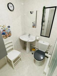 a bathroom with a sink and a toilet and a clock at Les Pins Marins, Proche plages in Saint-Jean-de-Monts +18 photos