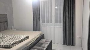 a bedroom with a bed and a large window at Harmony Apartman in Otilia