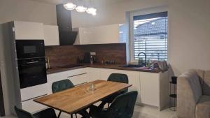 a kitchen with a wooden table and green chairs at Harmony Apartman in Otilia
