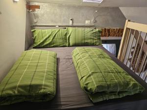 a bed with green sheets and pillows on it at Casa GiuBarElla in Vanzago