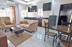 a living room with a couch and chairs and a kitchen at Résidence Inspire in Douala
