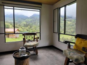 a room with two chairs and a table and large windows at Refugio rural MITA in Zipacón