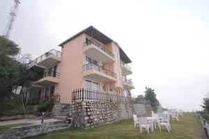 a building with white tables and chairs in front of it at Corbett Valley View in Tota Ām