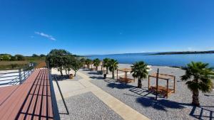 a row of benches next to the water with palm trees at Apartment House Liznjan in Ližnjan