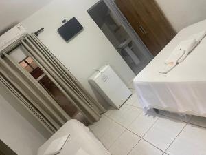 a bathroom with a toilet and a refrigerator in a room at Pousada Rozam in Olímpia