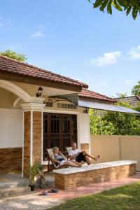 two people sitting on the porch of a house at Lilo House, Thaimueang Beach in Thai Muang