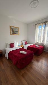 Ein Schlafzimmer mit zwei Betten, bezogen mit roter Bettwäsche und Holzboden in der Unterkunft Two Ducks in Rom