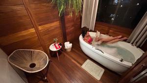 a woman laying in a bath tub in a room at Chale Allegra - Hidro Aquecida - Vista para o Lago in Venda Nova do Imigrante +57 photos