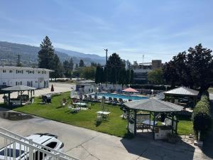 a resort with a swimming pool and tables and chairs at Empire Motel in Penticton