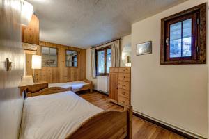 a bedroom with two beds and a dresser and windows at Chalet Les Frenes in Chamonix