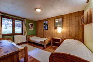 a bedroom with two beds in a room with wooden walls at Chalet Les Frenes in Chamonix