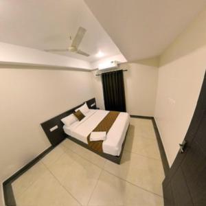 a bedroom with a bed in a white room at krishna suites guruvayur in Guruvāyūr +4 photos