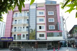 a pink building in the middle of a street at krishna suites guruvayur in Guruvāyūr