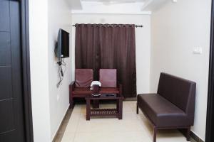 a living room with a couch and a chair at krishna suites guruvayur in Guruvāyūr